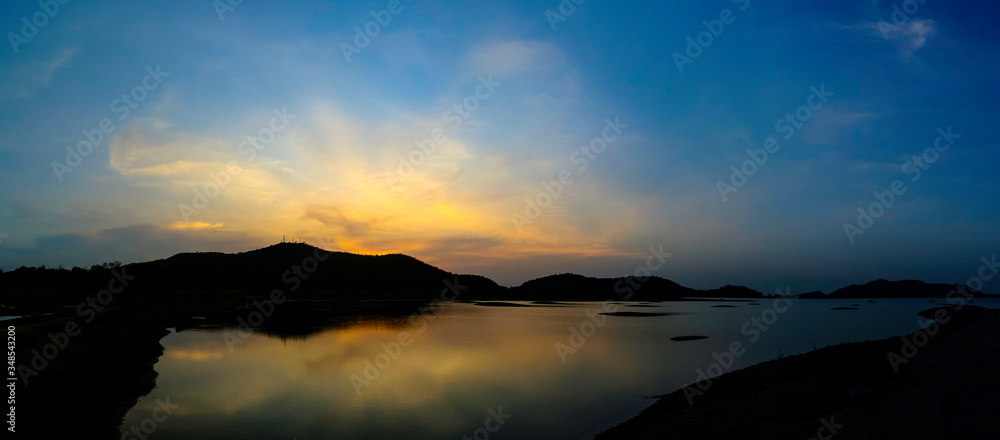 Dramatic sky at silhouette mountain with water surface foreground