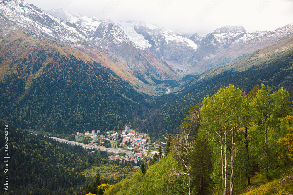 Obraz premium Dombay ski resort from the Mount Mussa Achitara, beautiful mountains landscape, small village and snowy peaks, Caucasus, Russia