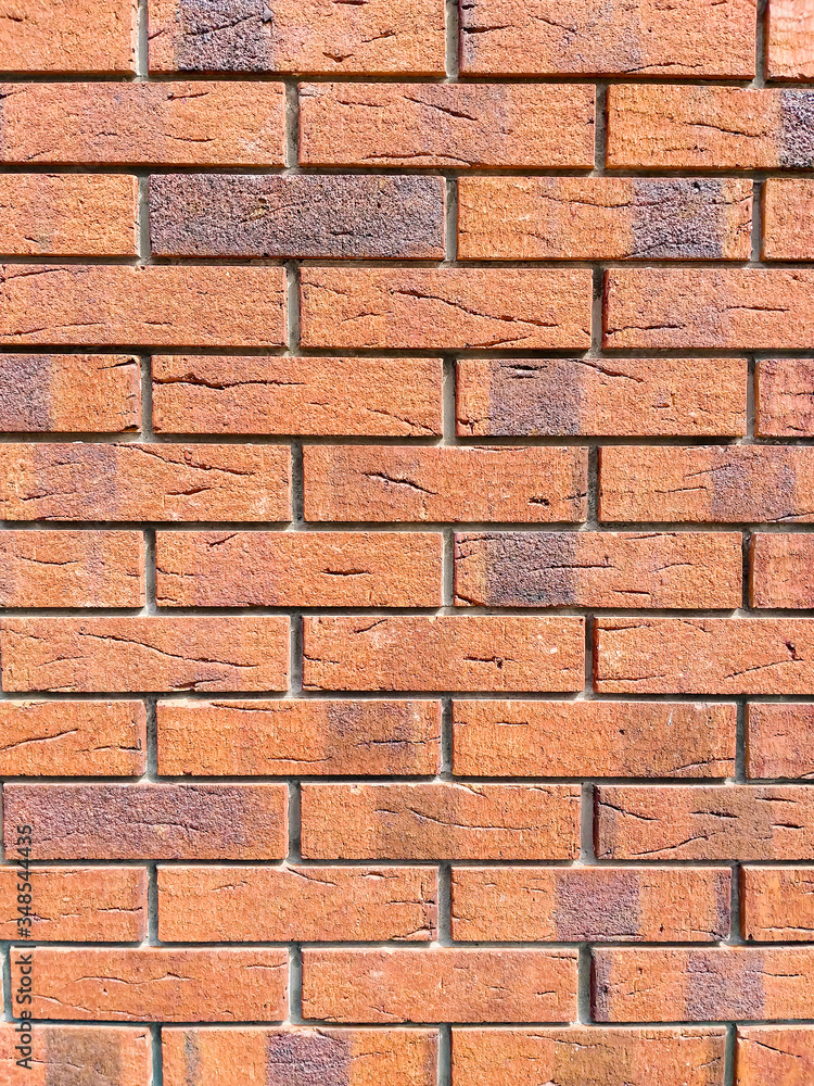 Obraz premium Brick wall background. Decorative brickwork from a smooth new brick. Copy space on the background of clay bricks for design work. Red brick laid in a flat masonry.