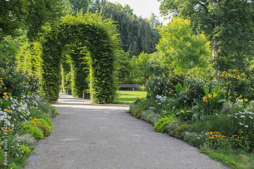 Vintage Garten und Landschaftsbau: Laubengang und mit Blumenbeeten gesäumter Fussweg in einem Park 	