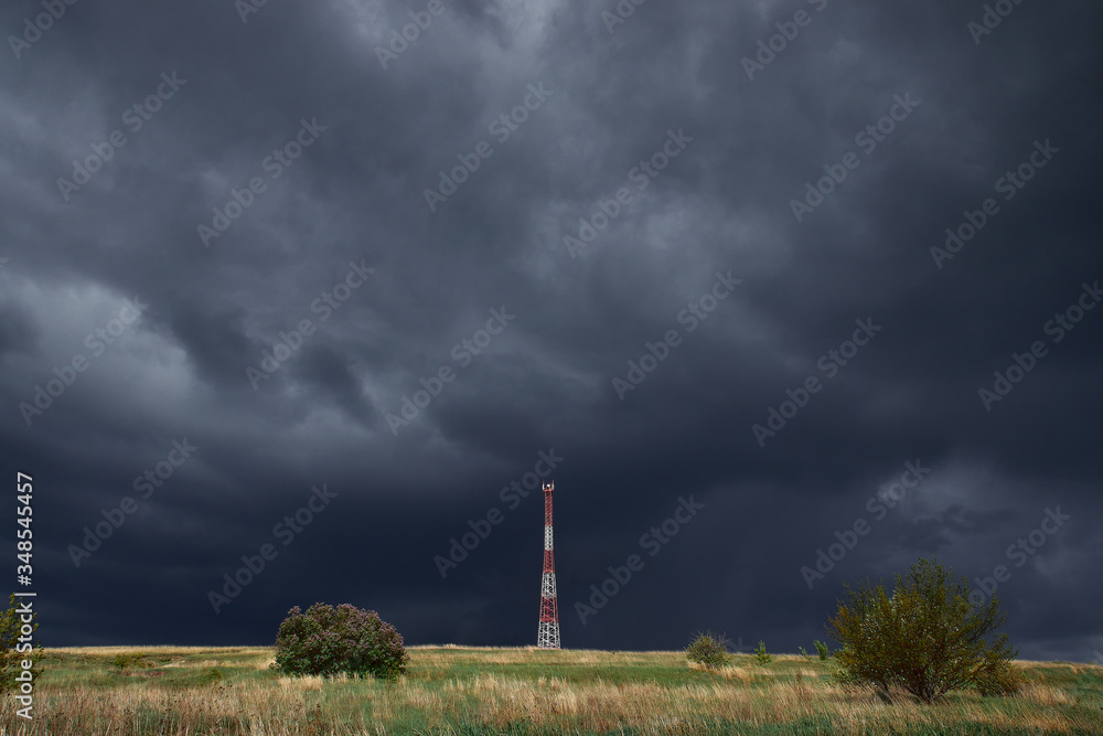 Communication tower on a hill against the background of dark sky. Base station outside the city