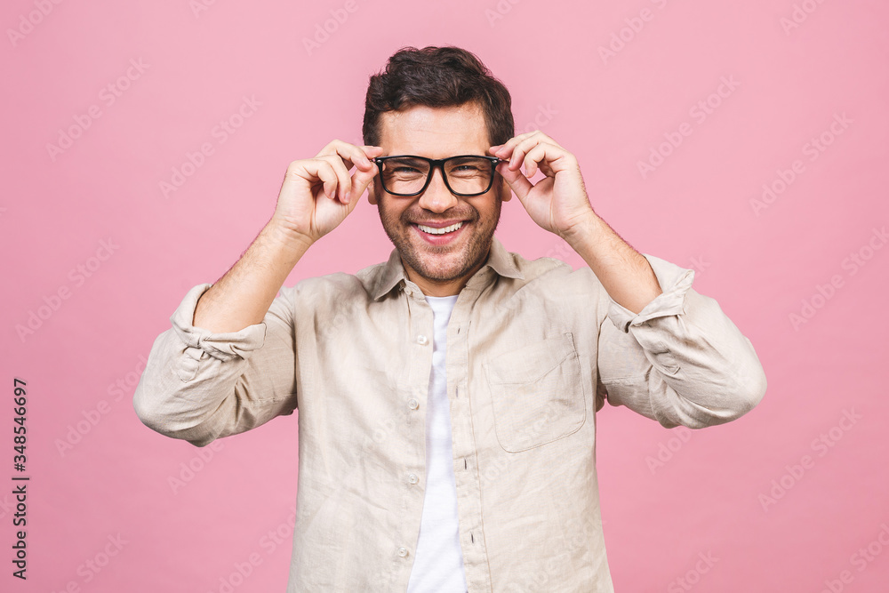 A portrait of young smiling handsome business man in casual shirt isolated on pink background touching his glasses. A portrait of young smiling handsome business man in casual shirt isolated on pink background touching his glasses.