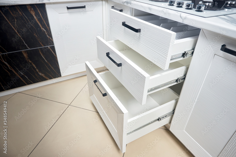 Solution for placing kitchen utensils in modern kitchen - horizontal sliding pullout drawer shelves storage in cupboard for kitchenware cookware under oak countertop gas hob with copyspace. Solution for placing kitchen utensils in modern kitchen - horizontal sliding pullout drawer shelves storage in cupboard for kitchenware cookware under oak countertop gas hob with copyspace.