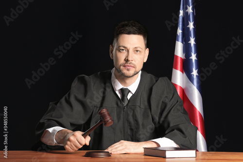 Male judge at table on dark...
