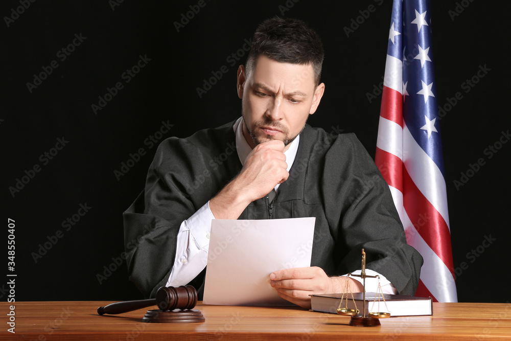 Male judge reading documents at table on dark background Male judge reading documents at table on dark background