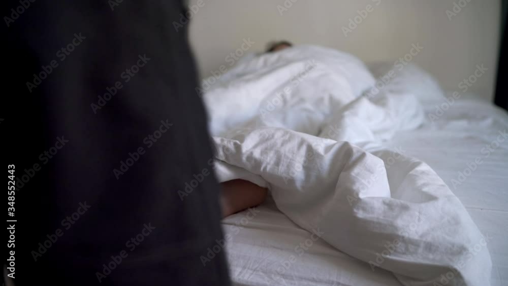 Man wakes a woman in the morning at home, female feet sticking out from under duvet in bed. Man wakes a woman in the morning at home, female feet sticking out from under duvet in bed.