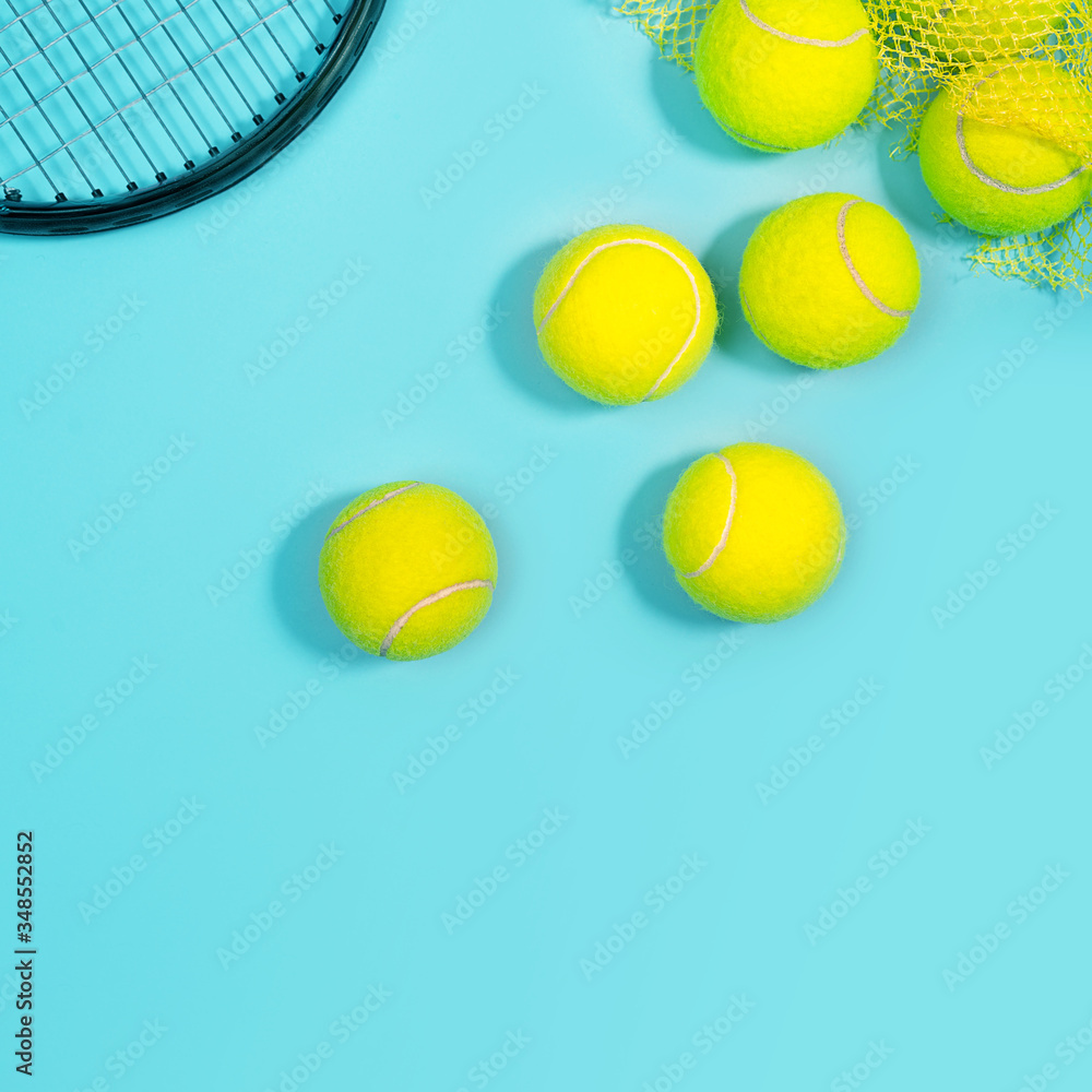 Sport layout with tennis balls and racquet close up on blue tennis court.. Copy space, selective focus. Blue and yellow.