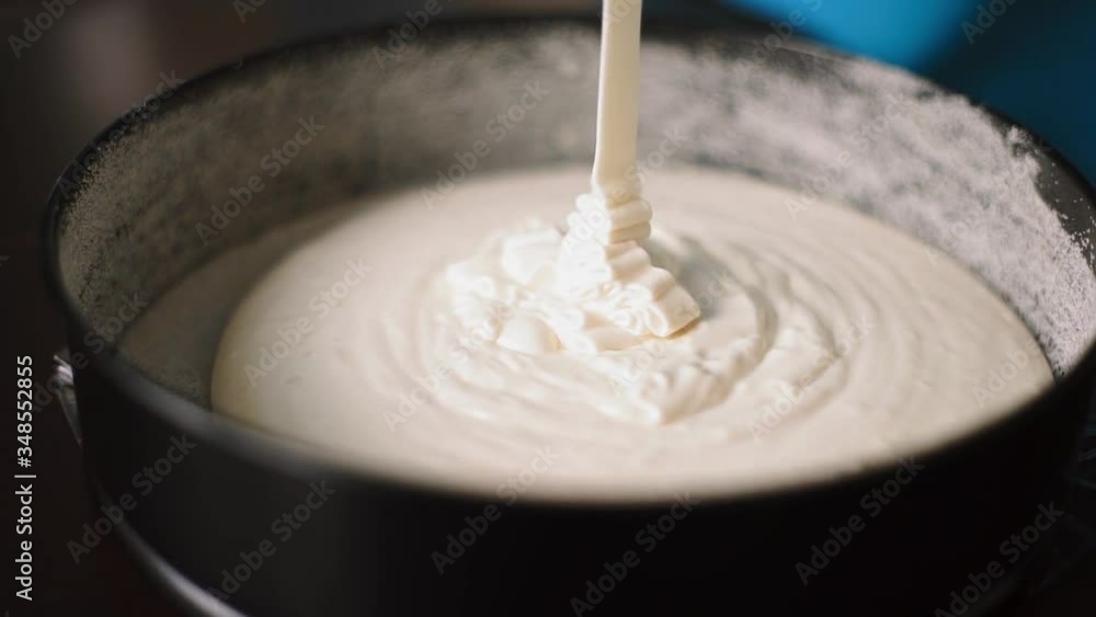 baker pours batter into the form for baking baker pours batter into the form for baking