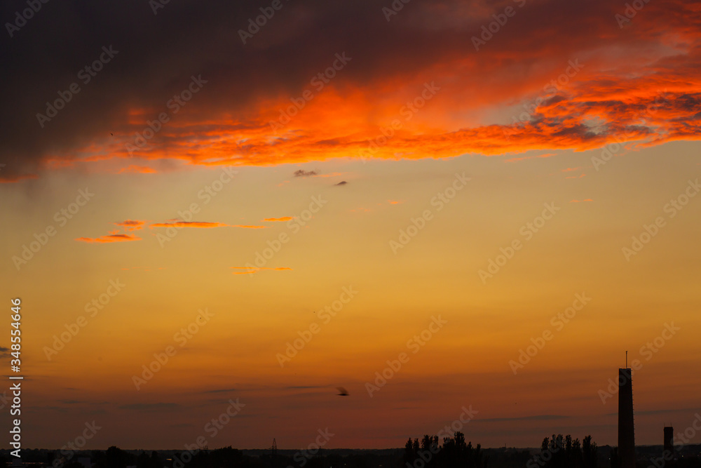 Fototapeta premium Black thunderclouds at sunset. Bright orange sunset and dark clouds. Storm sky