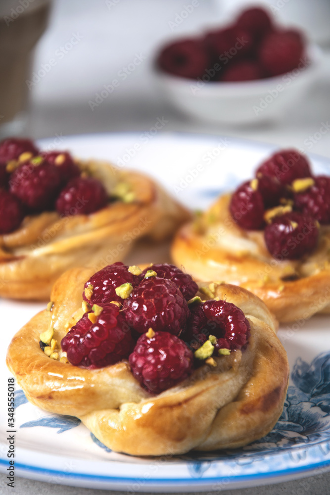Close-up of French pastry, fresh baked puff pastry buns with raspberries and cappuccino coffee on white table, served breakfast Close-up of French pastry, fresh baked puff pastry buns with raspberries and cappuccino coffee on white table, served breakfast
