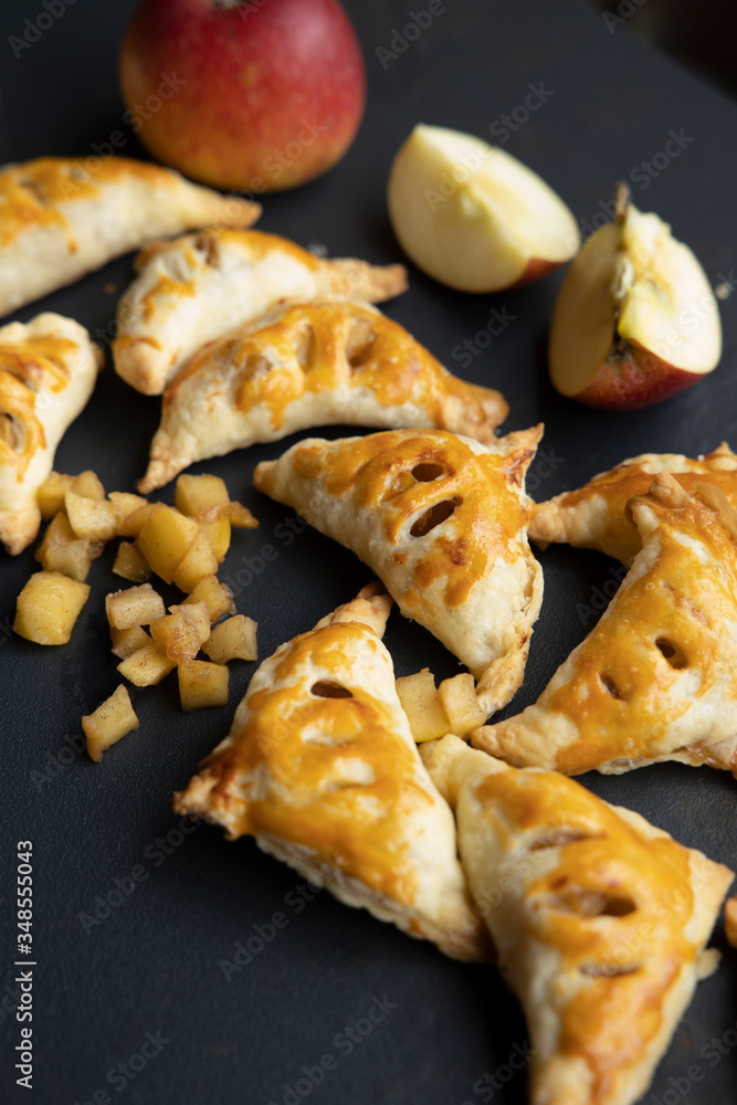 apple turnover on a dark concrete table with apple, horizontal view from above, flatlay, free space