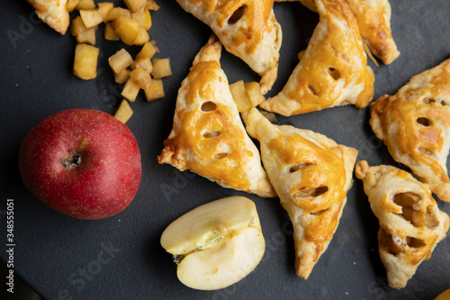 apple turnover on a dark concrete table with apple, horizontal view from above, flatlay, free space photo