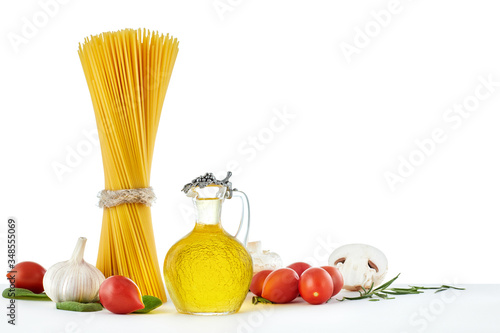 italian raw dry pasta spaghetti, olive oil and vegetables isolated on white background. copy space. Top view. Healthy diet