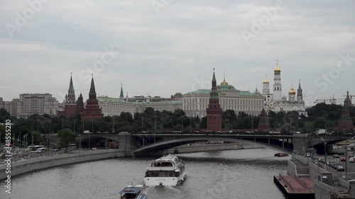 View of the Bolshoy Kamenny Bridge when the boat passes on a cloudy day. The Grand Kremlin Palace and The Ensemble of a Bell Tower of Ivan in the background.