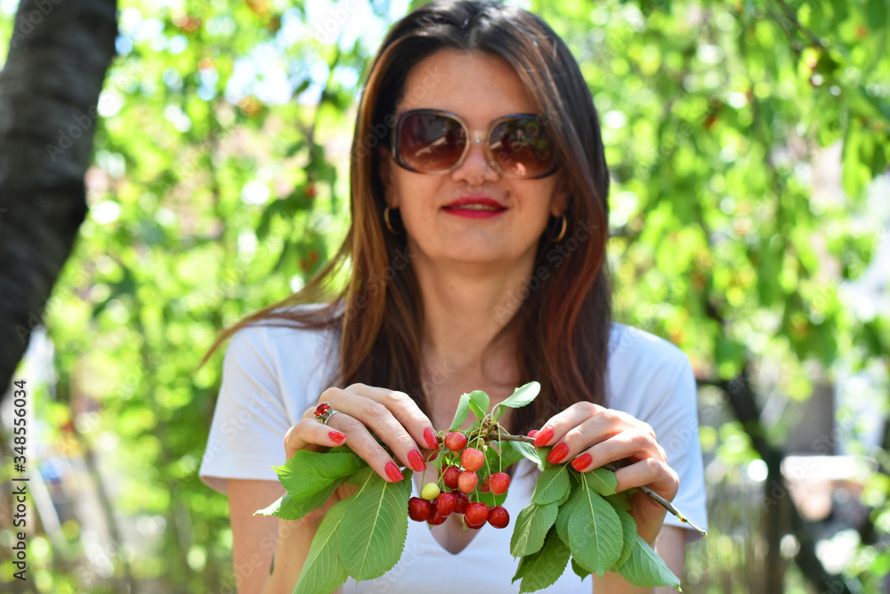 Branch of ripe cherries in women's hands. Portrait of beautiful woman with red cherry Branch of ripe cherries in women's hands. Portrait of beautiful woman with red cherry