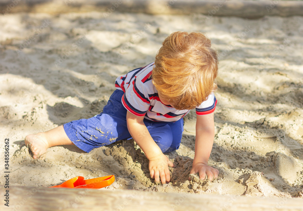 Cute child plays in the sandbox. Little boy plays In the yard Cute child plays in the sandbox. Little boy plays In the yard