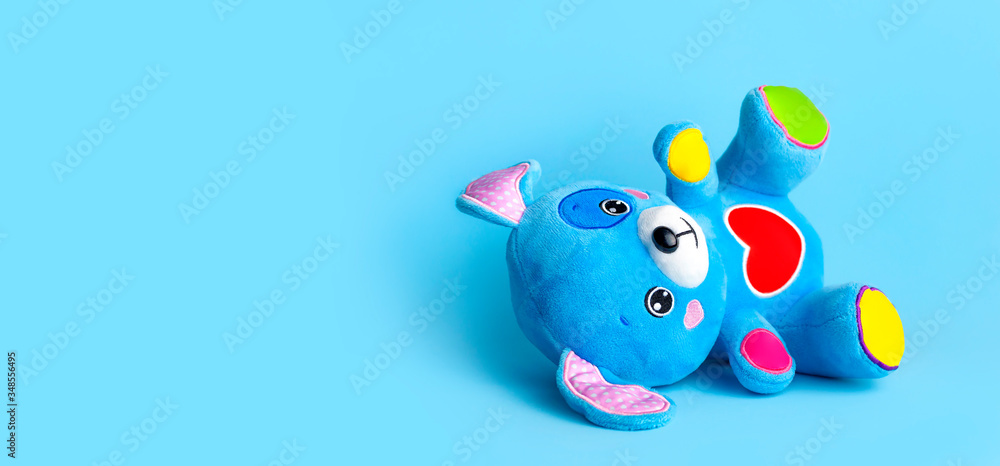 Blue soft children's toy puppy with funny ears, multi-colored paws and red heart on blue background flat lay copy space. Plush toy dog, baby friend, children's play item, happy childhood Blue soft children's toy puppy with funny ears, multi-colored paws and red heart on blue background flat lay copy space. Plush toy dog, baby friend, children's play item, happy childhood