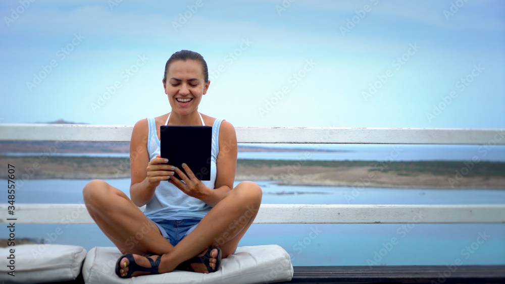 Fototapeta premium Relaxed and cheerful work and vacation outdoor portrait of happy young woman using tablet