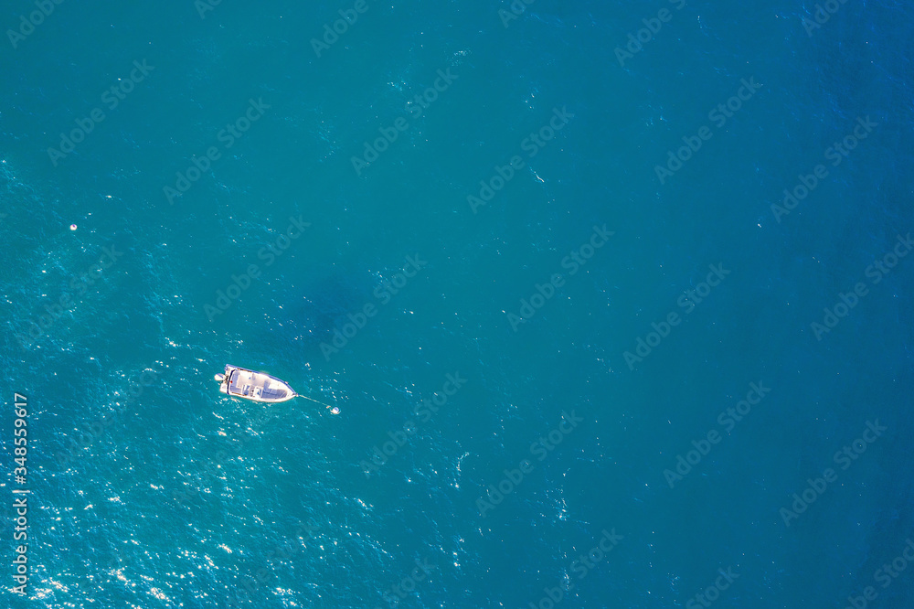 top view of a white boat anchored in the blue sea