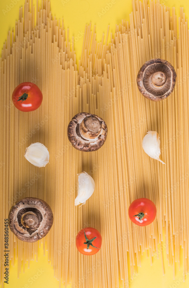 Spaghetti pasta with ingredients for cooking pasta on a yellow background. Colorful top and closeup Spaghetti pasta with ingredients for cooking pasta on a yellow background. Colorful top and closeup