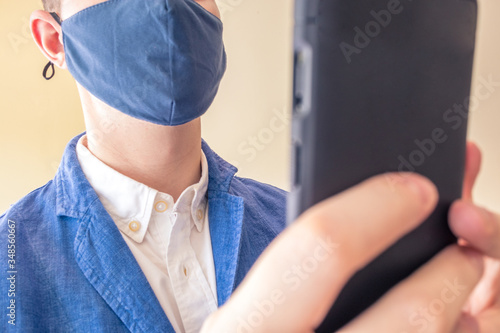Business elegant man using a phone / mobile for taking a photo or sending a message with a face mask on.