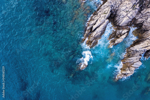 aerial top view of rocky coast with clear blue sea
