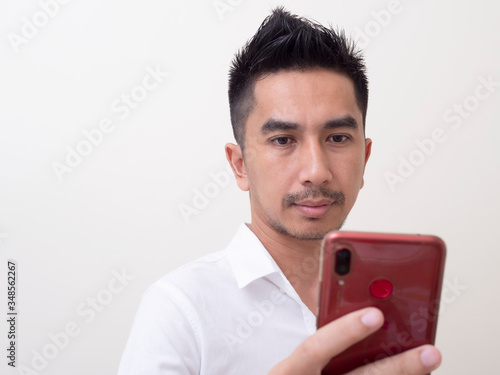 A portrait of an Asian young man holding a hanphone