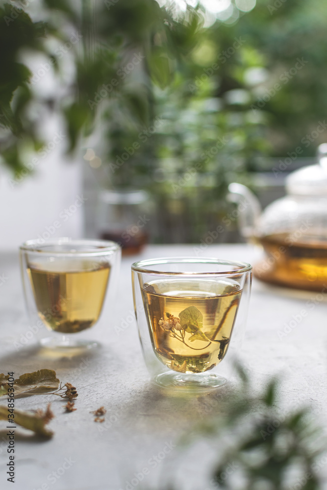 Summer linden flowers tea with splashes on white light table with bokeh