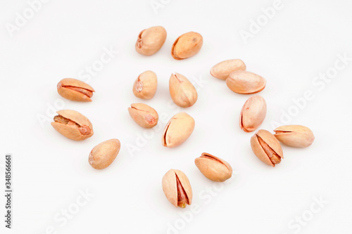 Organic pistachio nuts scattered on white background