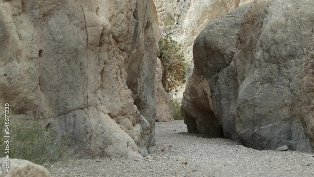 A male hiker walks through a narrow section of Fall Canyon in Death Valley National Park in California. A male hiker walks through a narrow section of Fall Canyon in Death Valley National Park in California.