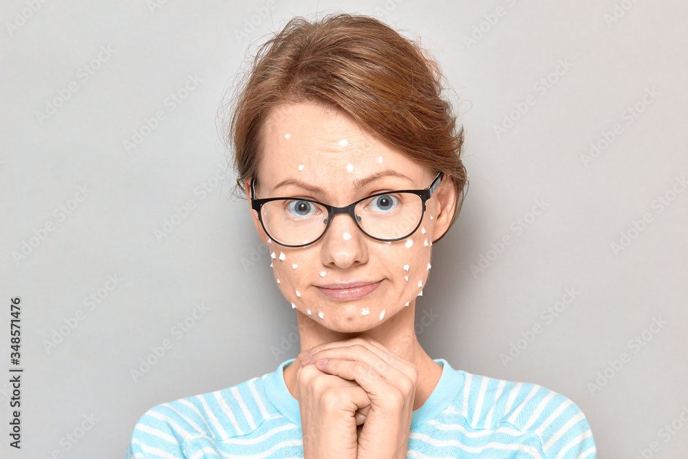 Portrait of dreamy sad girl with white drops of face cream on skin Portrait of dreamy sad girl with white drops of face cream on skin