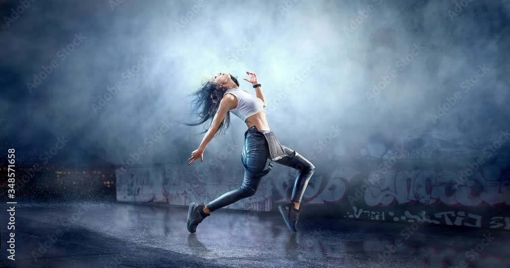 Female street dancer in a action with a graffity wall behind the fog on a backgroung. Female street dancer in a action with a graffity wall behind the fog on a backgroung.