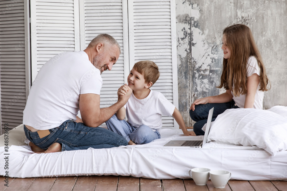 Father and son fight in their arms, and his daughter watches them. They are home on self-isolation. Father and son fight in their arms, and his daughter watches them. They are home on self-isolation.