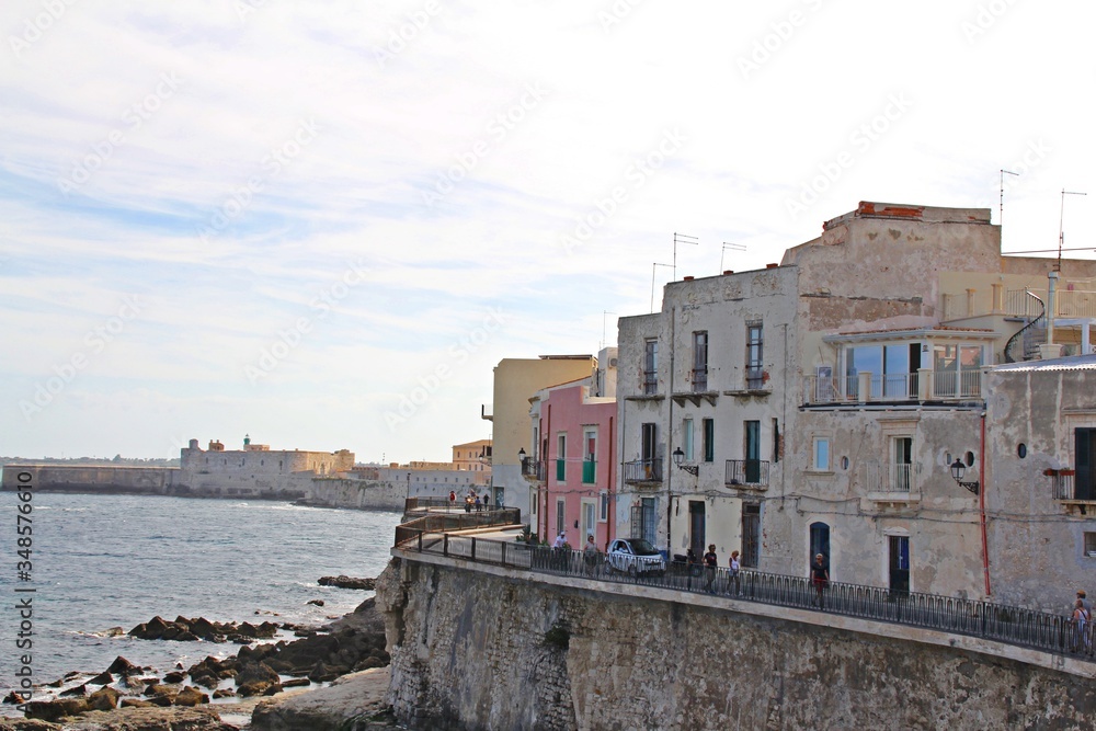 Sicily, Syracuse, old classical buildings on the seashore in Ortigia, street on the shore, buildings, sea and volcanic rocks