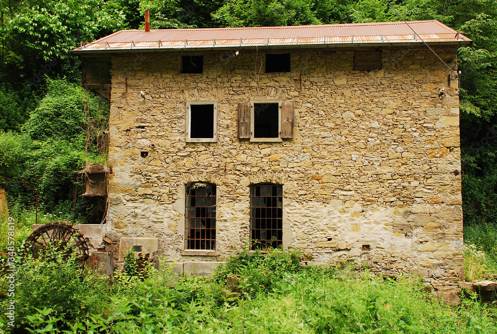 An old abandoned mill near Salino in Friuli, north east Italy. It has a water wheel mounted vertically on a horizontal axis.
