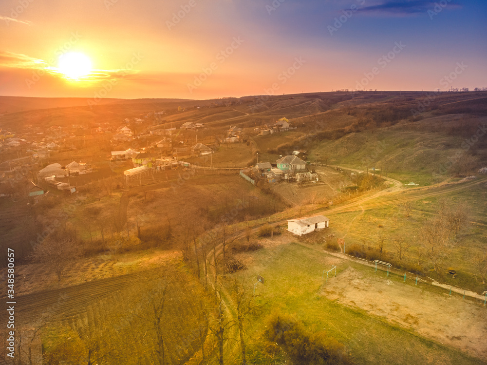 Fototapeta premium An old house on the edge of the village and a beautiful sunset. Aerial view