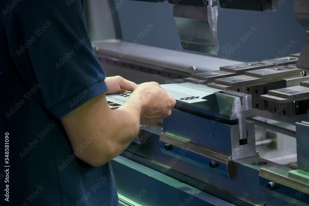 Naklejka premium The operation of hydraulic bending machine with technician. The automotive sheet metal manufacturing process by bending machine with technician operator.