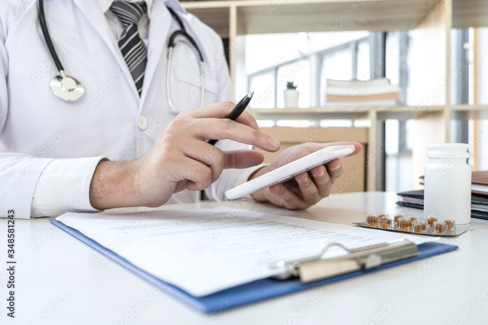 Doctor working with digital tablet in clinic and medical stethoscope, medicine on clipboard on desk Doctor working with digital tablet in clinic and medical stethoscope, medicine on clipboard on desk