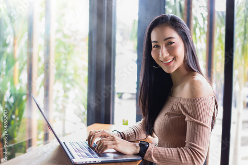 Asian businesswomen are using notebook computers for working from home.She is smile happy and enjoys working.