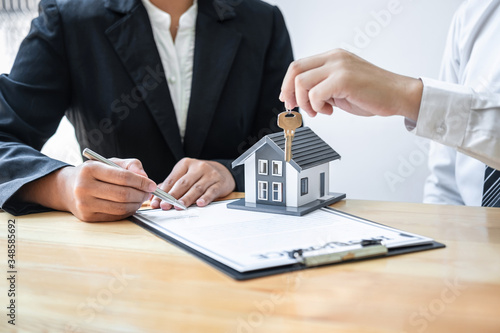 Home Insurance and Real estate investment concept, Sale agent giving house key to new client after signing agreement contract with approved property application form