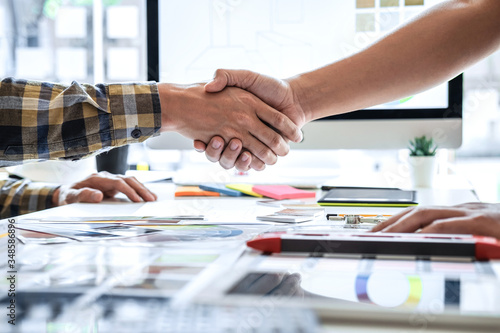 Team of young Interior graphic designer shaking hands after working sketching on color swatch, discussing of house project at modern office, creative work place inspiration and imagine