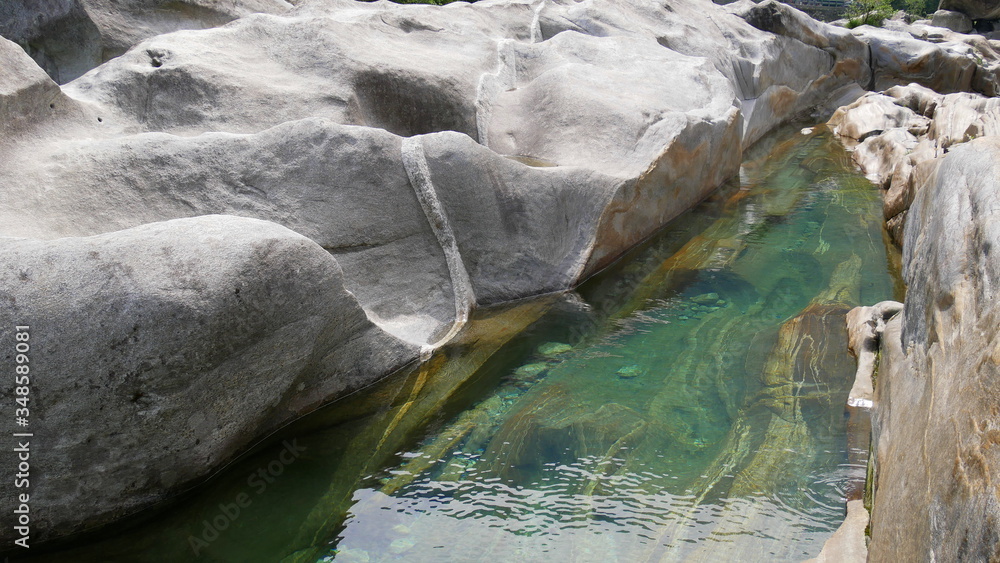 Fototapeta premium vom Wasser geformte Felsen mit smaragdgrünem Wasser im Verzasca Tal, einem Seitental am Lago Maggiore
