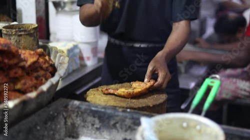 Famous butter tandoori chicken at Aslam Chicken in Jama Masjid, Old Delhi. Man chopping meat with a big knife. Cutting chicken in pieces with a cleaver. Ramadan Eid food 2020.