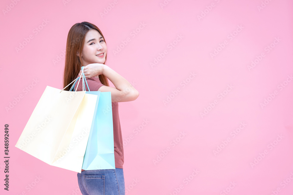Portrait of Beautiful young smiling happy woman holding shopping bags isolated pink background Portrait of Beautiful young smiling happy woman holding shopping bags isolated pink background