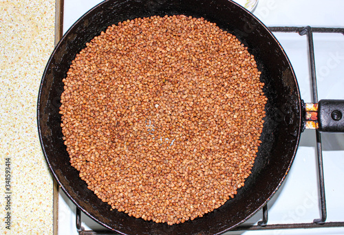 Frying buckwheat in a pan on the stove. The preparation of wholesome food. photo