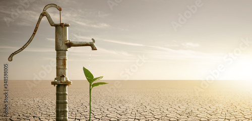 Water flows from the rusty water pump to the plant in the desert. Drought and water scarcity caused by global warming