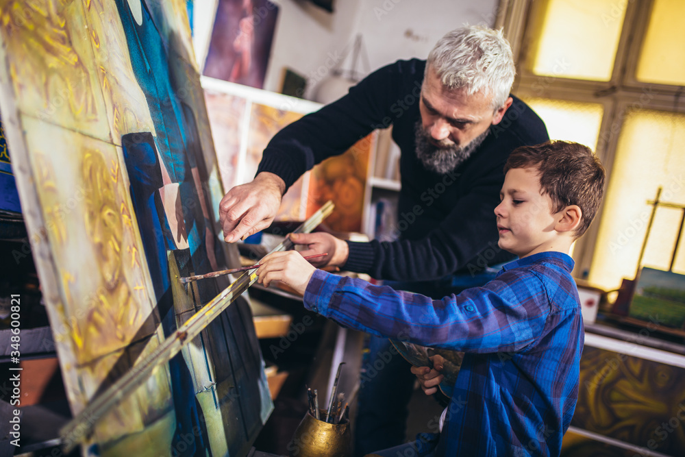 Father and son working and painting together in art studio