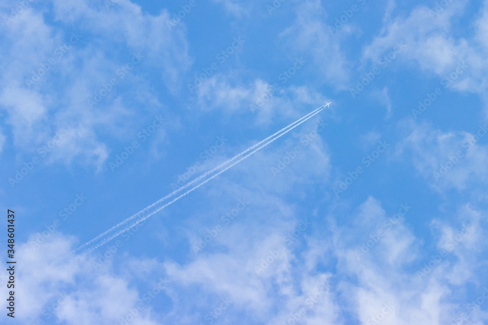 the plane flies among the clouds against the blue sky, leaving a trail behind it. The concept of ending the coronavirus pandemic and increasing air travel. the plane flies among the clouds against the blue sky, leaving a trail behind it. The concept of ending the coronavirus pandemic and increasing air travel.
