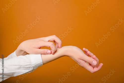 Concept skin allergy. Close up of woman scratches her hands isolated on brown background with copy space. Signs of dermatitis and scabies.