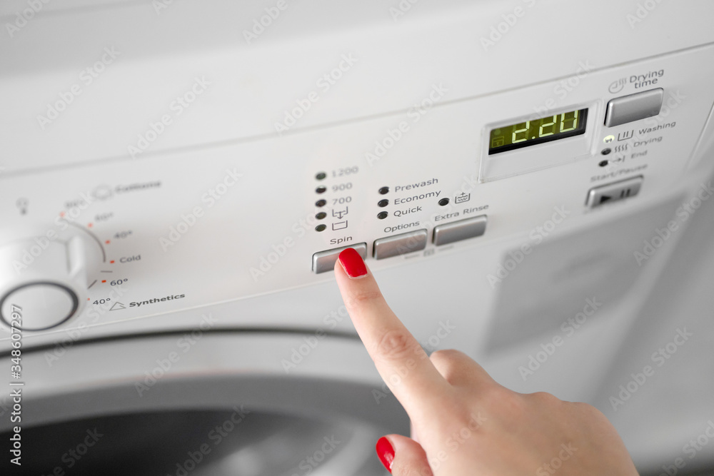 The girl sets the washing program for the washing machine. The girl sets the washing program for the washing machine.